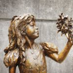 Brass Stautue of young girl holding up a bunch of flowers