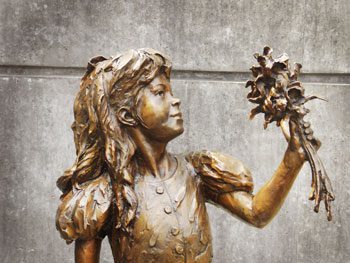Brass Stautue of young girl holding up a bunch of flowers