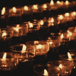 Four rows of white lit candles in clear glss holders