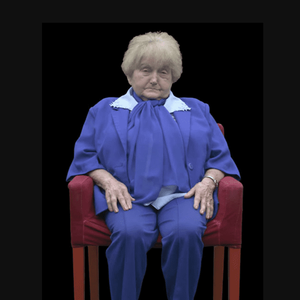 Holocaust survivor Eva Kor sitting in a red chair being interviewed for her DIT