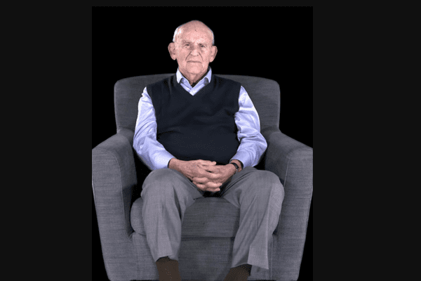 Holocaust liberator AlAN Moskin sitting in a gray chair while being filmed for DIT.