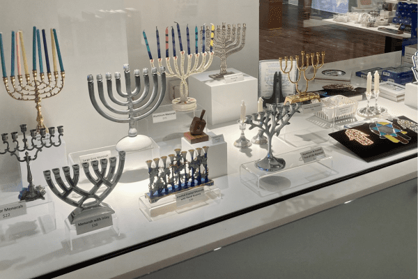 A glass case featuring menorahs in multiple colors and sizes.